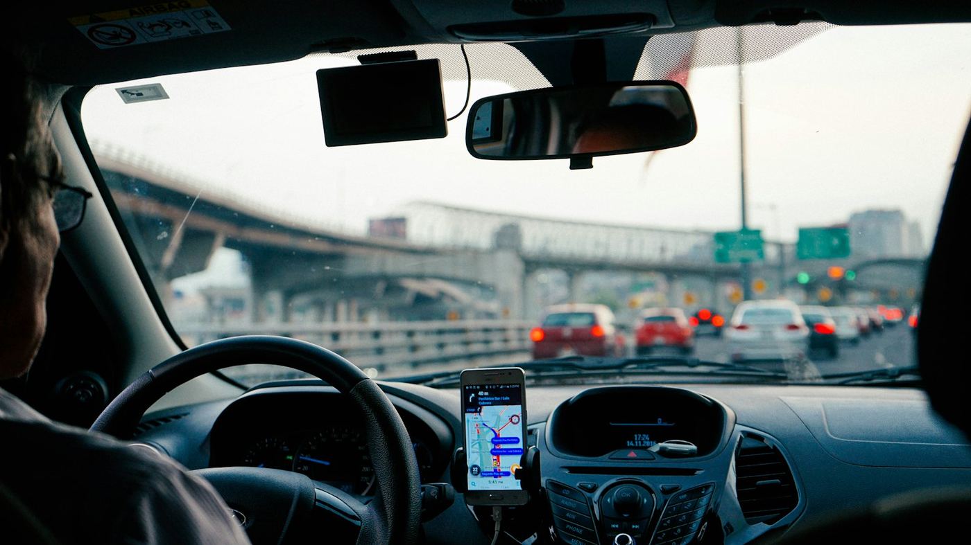 Telefoon in een houder op het dashboard van een auto, onderweg in het verkeer